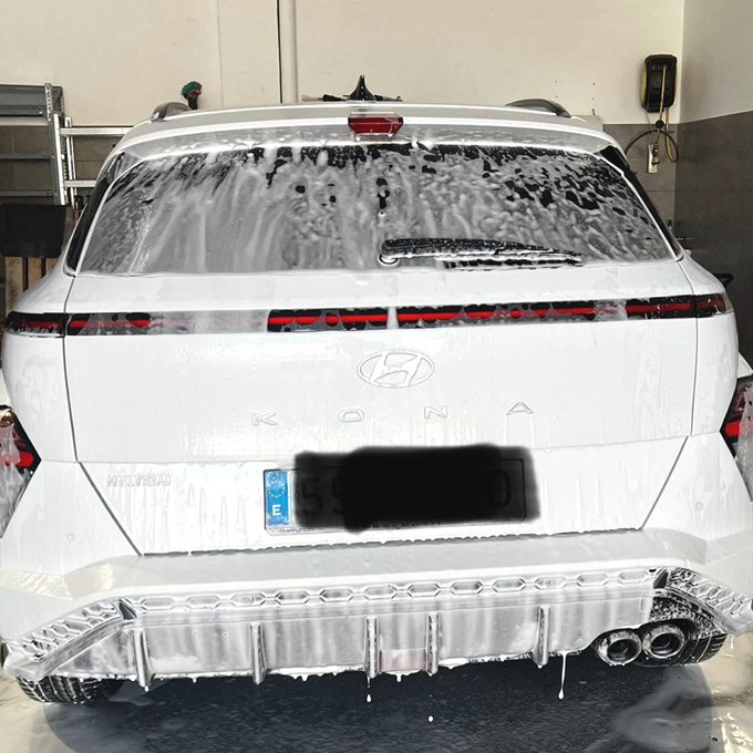 Coche cubierto de espuma en el box de lavado del taller